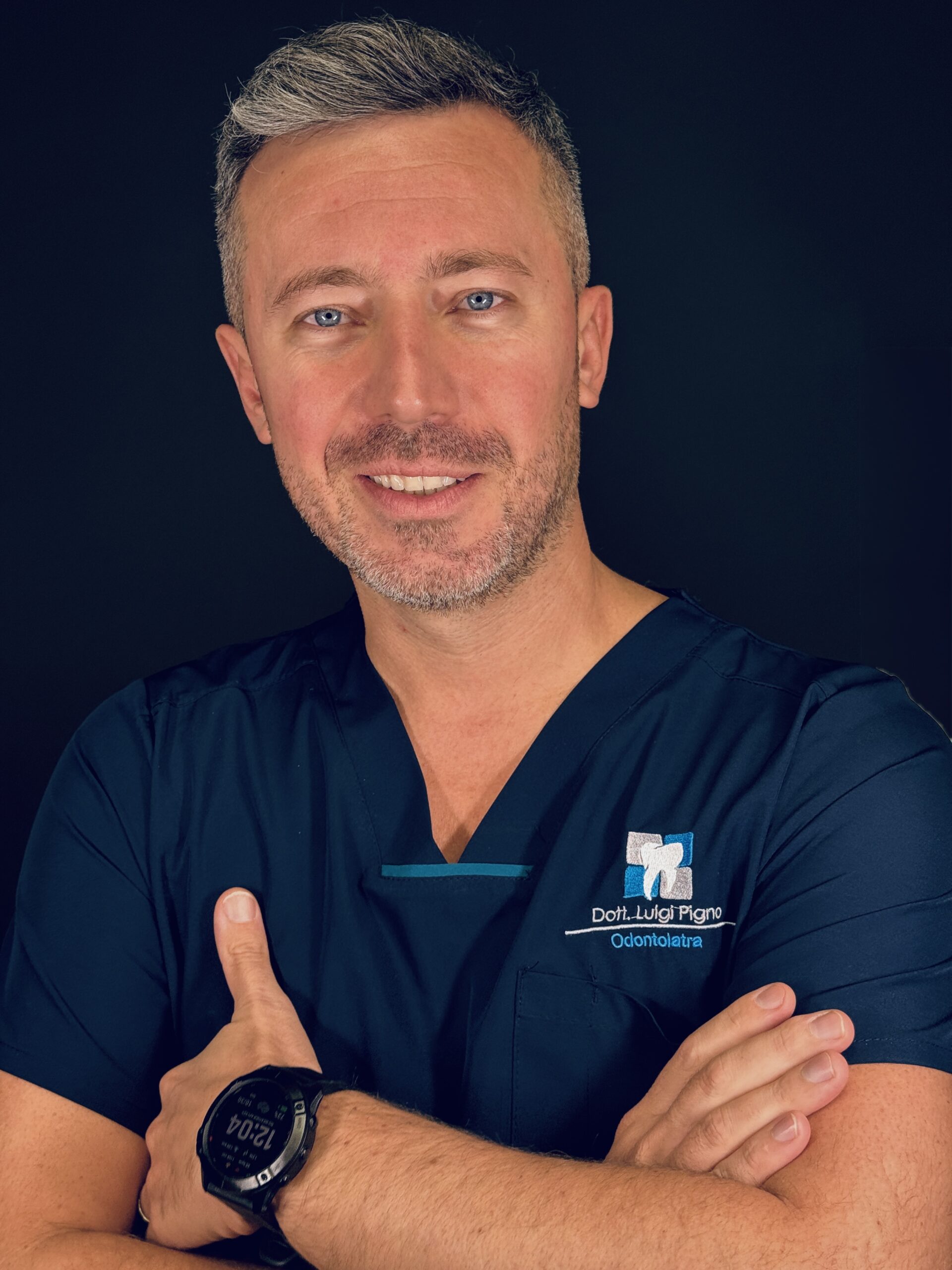 Ritratto professionale in divisa clinica su sfondo nero nello studio odontoiatrico di Torre del Greco